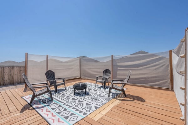 Spacious outdoor seating area featuring a firepit and privacy screens, perfect for gatherings and relaxation.