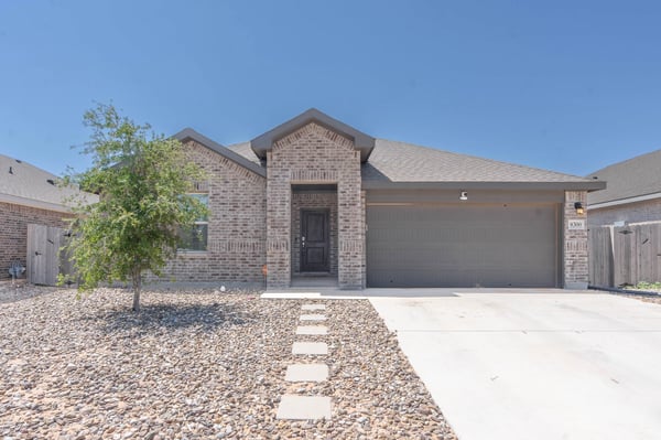 This modern brick home features a spacious driveway, low-maintenance landscaping, and a welcoming entrance.