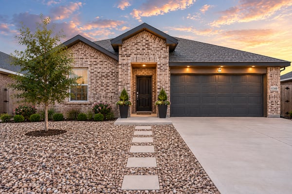 Contemporary brick home featuring a landscaped front yard and modern garage, perfect for suburban living.