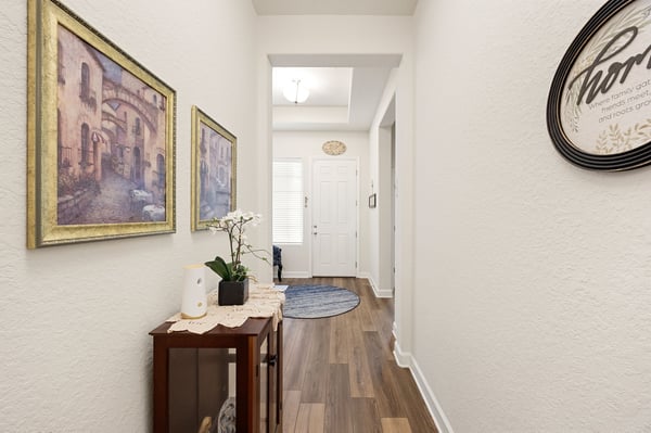 Bright hallway showcasing art and tasteful decor, leading to an inviting living space and front door.