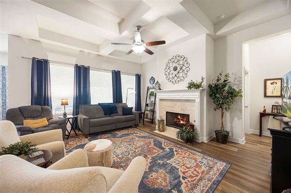 Bright and inviting living room featuring a cozy fireplace, coffered ceilings, and abundant natural light.