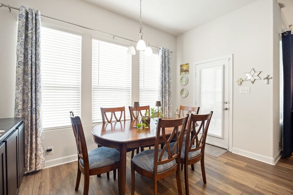 Bright dining area features large windows, modern fixtures, and a spacious table, perfect for gatherings.