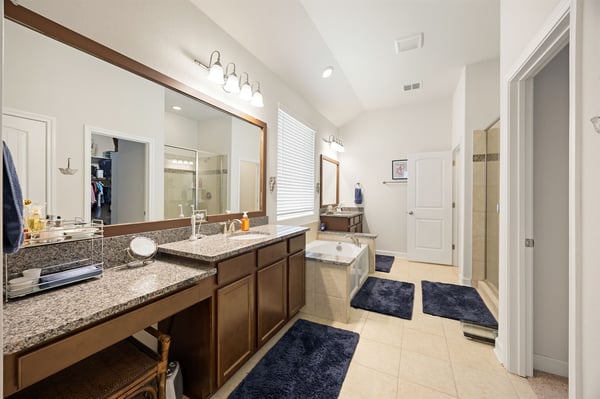 Spacious bathroom featuring dual vanities, ample storage, and a relaxing soaking tub in a bright setting.