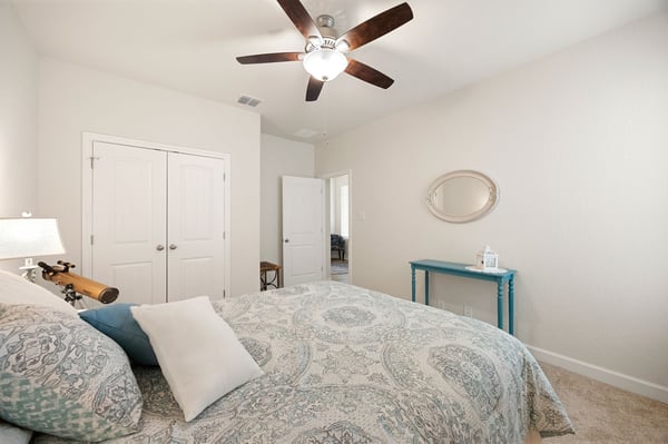 Spacious bedroom featuring a ceiling fan, natural light, and a functional layout with ample storage options.