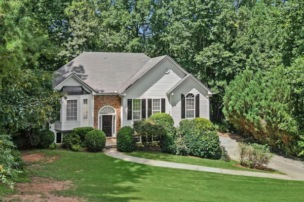 Spacious home surrounded by lush greenery, featuring ample natural light and inviting outdoor spaces.