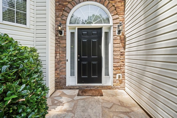 Welcoming black door framed by stone and siding, leading to a inviting entryway.