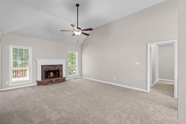 Spacious living area features a cozy fireplace and large windows offering ample natural light.