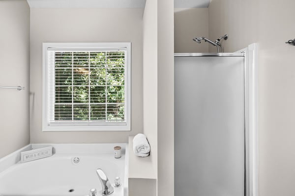 Spacious bathroom featuring a soaking tub and separate shower, with natural light from the large window.