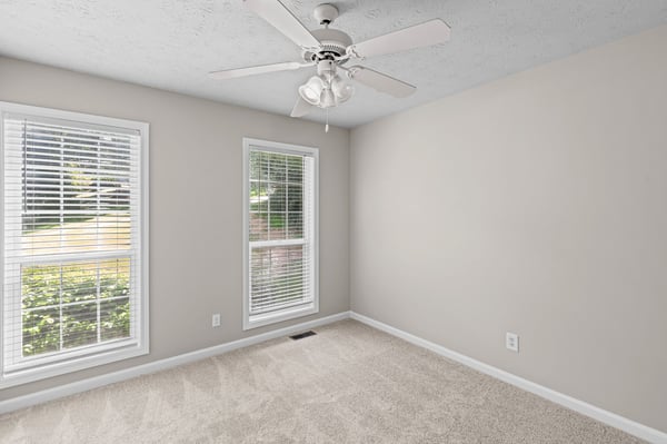 Bright and spacious room featuring large windows, new carpeting, and a ceiling fan for comfort.