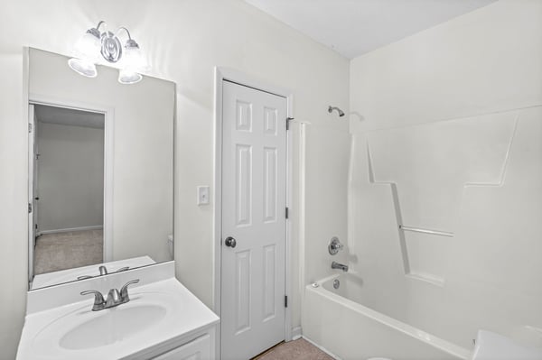 Bright and clean bathroom featuring a spacious bathtub and convenient dual-sink vanity. Ideal for family living.