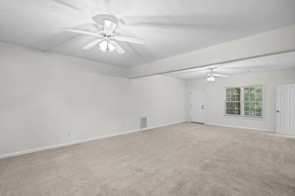 Spacious living area featuring soft carpeting and ample natural light, ready for your personal touch.