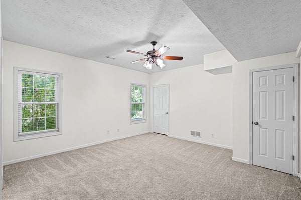 Spacious room featuring natural light, a ceiling fan, and versatile potential for various layouts.