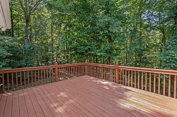 Spacious deck overlooking a lush, wooded area, perfect for outdoor gatherings and relaxation.
