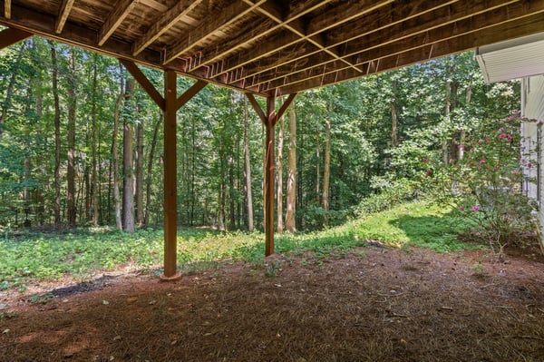 Spacious under-deck area surrounded by lush woods, ideal for outdoor gatherings or storage solutions.