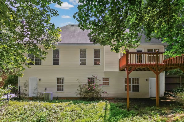 Spacious home with a large deck overlooking a private, wooded backyard, perfect for outdoor gatherings.