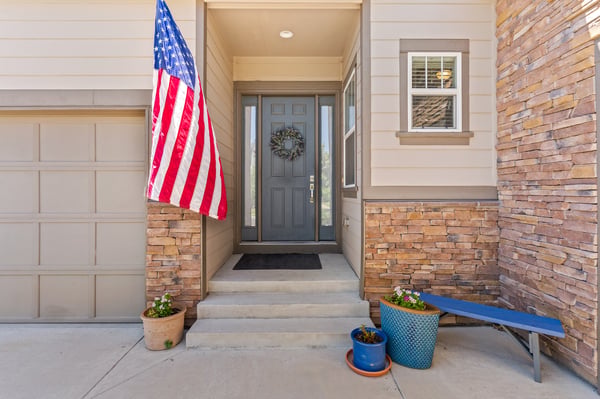 This inviting entrance features unique stone accents and a welcoming American flag, perfect for curb appeal.