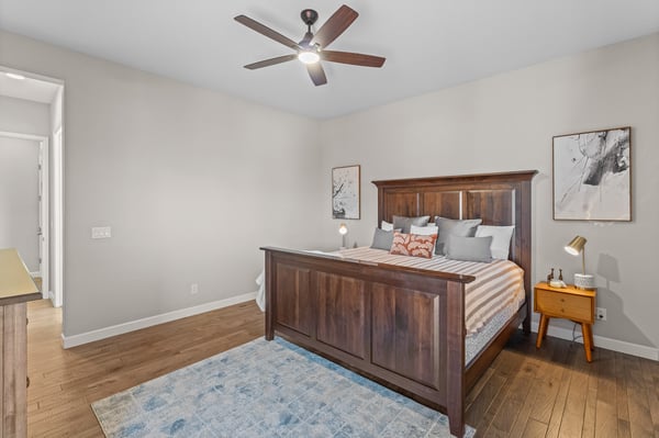 Spacious bedroom featuring warm wood tones, modern furnishings, and a ceiling fan for added comfort.