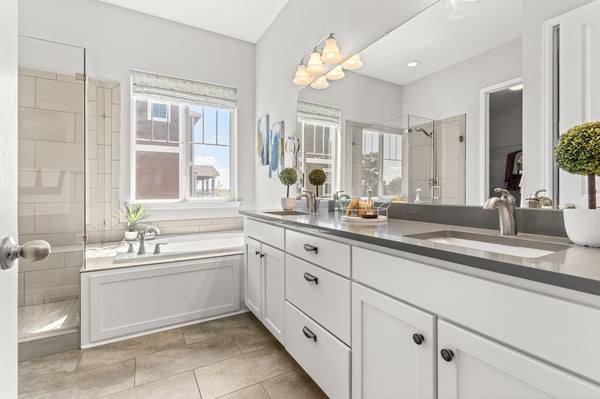 Bright and spacious bathroom featuring dual sinks, abundant natural light, and modern finishes throughout.