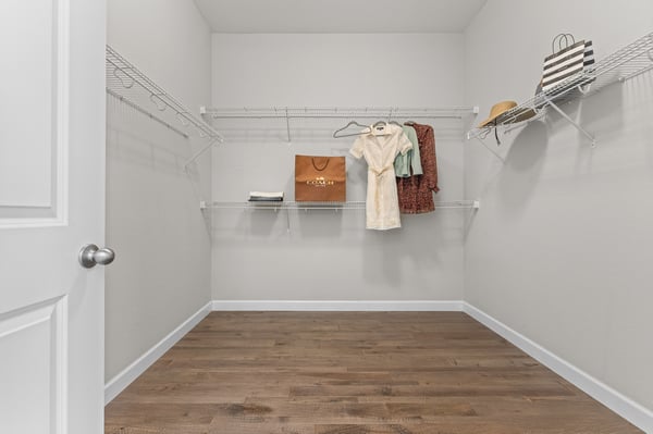 Spacious walk-in closet featuring ample shelving and a wood-like floor, ideal for organized storage.