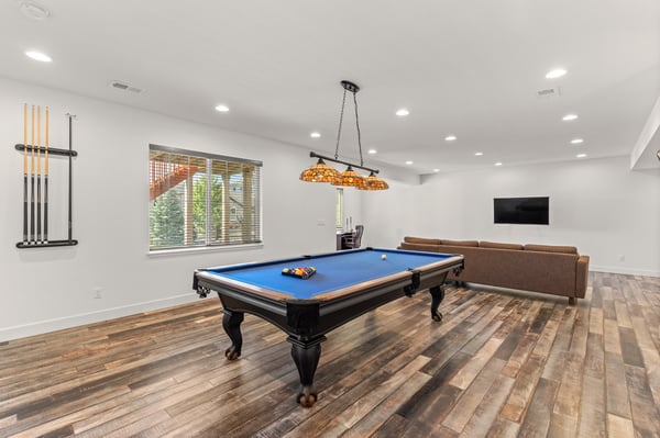 Spacious game room featuring a billiards table, cozy seating, and large windows for natural light.