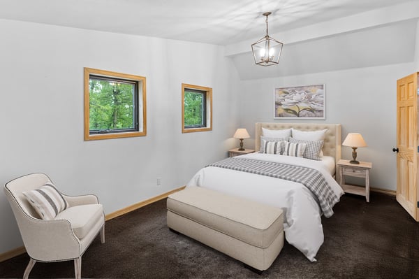 Cozy bedroom featuring a comfortable bed, ample natural light, and distinctive window designs for a unique touch.
