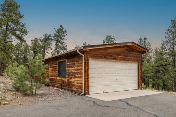 Discover a rustic cabin surrounded by trees, offering a peaceful retreat with modern convenience and garage.
