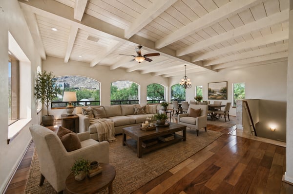 Bright and airy living space features exposed beams, ample natural light, and a seamless flow to dining areas.