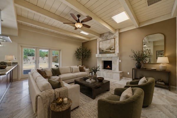 Spacious living area featuring vaulted ceilings, a stone fireplace, and seamless outdoor access for entertaining.