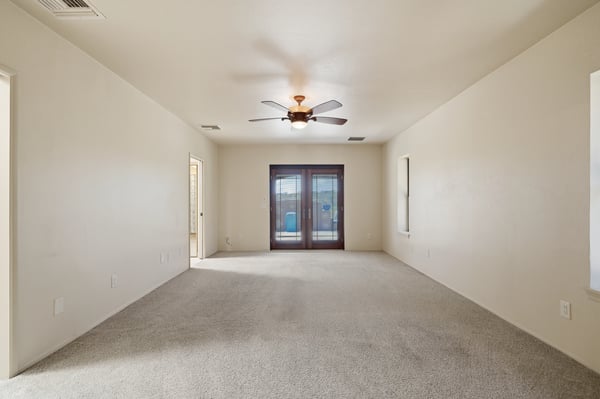 Spacious living area with natural light, featuring a ceiling fan and direct access to the outdoors.