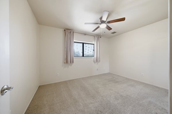 Spacious room featuring a ceiling fan and large window, perfect for personalized design and comfort.
