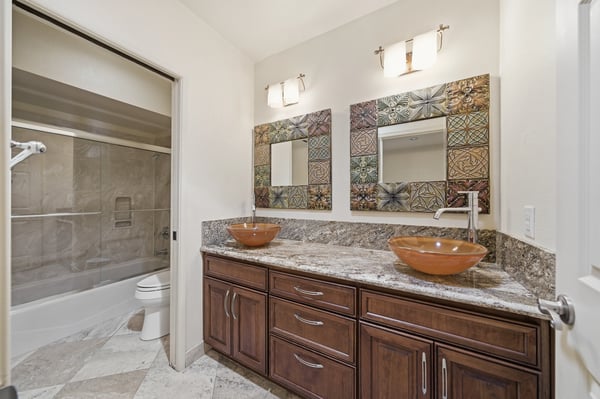 Bright bathroom featuring dual vessel sinks, modern fixtures, and a spacious layout with stylish tile accents.