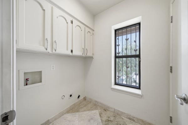 Bright and functional laundry room featuring ample cabinetry and a sizable window for natural light.