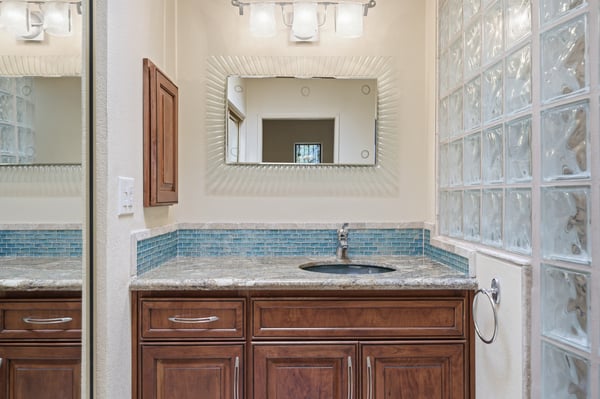 This modern bathroom features sleek cabinetry, contemporary fixtures, and a distinctive glass block wall for natural light.