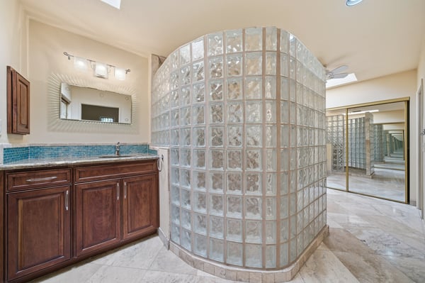 Modern bathroom featuring a unique glass block shower, sleek cabinetry, and ample natural light throughout.
