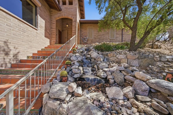 Experience a unique entry with natural stone landscaping and a welcoming water feature, leading to your new home.