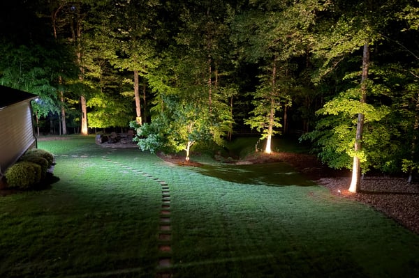 Discover a beautifully illuminated backyard featuring lush greenery and scenic pathways, perfect for evening gatherings.