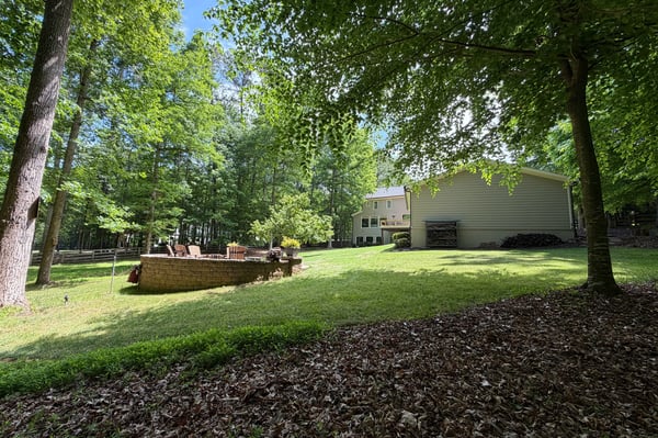 Spacious backyard surrounded by trees, perfect for outdoor gatherings and relaxation in a peaceful setting.