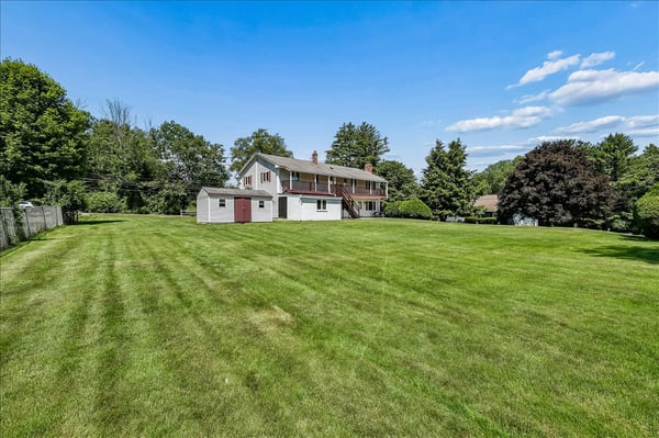 Spacious home on a vast, lush lawn surrounded by mature trees, perfect for outdoor activities and gardening.