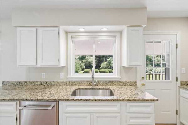 Modern kitchen with granite countertops, ample natural light, and views of the beautifully landscaped yard.
