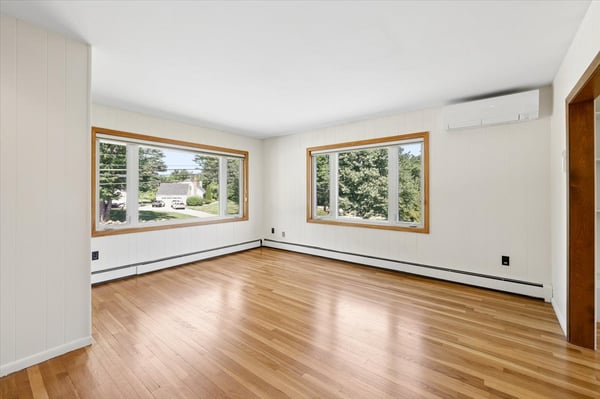 Bright and spacious living area featuring large windows and hardwood floors, perfect for relaxation and gatherings.