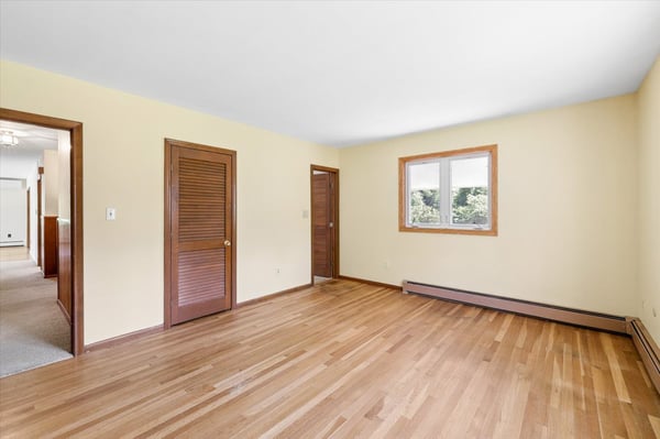 Spacious room featuring hardwood floors, natural light, and access to nearby rooms, ideal for versatile living.