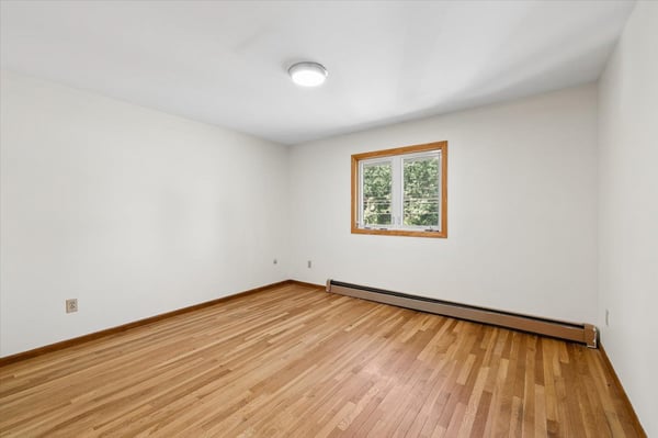 Spacious room featuring hardwood floors and a bright window, perfect for personalization and creativity.