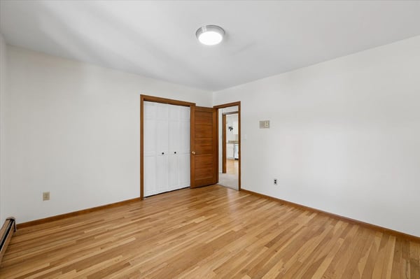 Light-filled room with hardwood floors, featuring ample closet space and simple, versatile decor options.