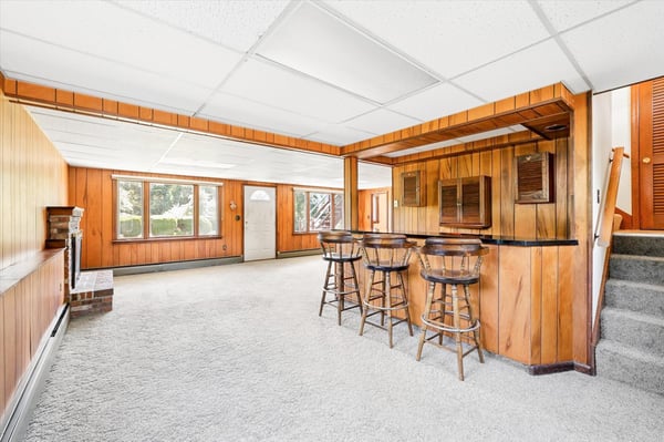 Spacious basement with built-in bar, large windows, and versatile layout perfect for entertaining or relaxation.