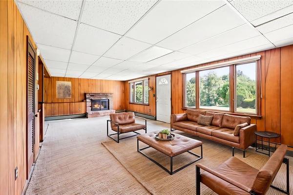 Spacious living area featuring ample natural light, a cozy fireplace, and views of the surrounding greenery.