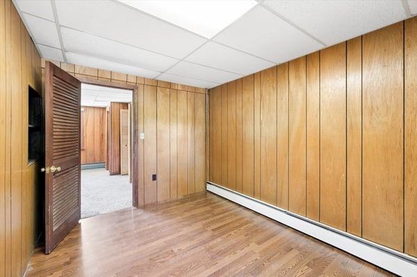 Spacious room featuring wood paneling, natural light, and convenient access to additional living areas.