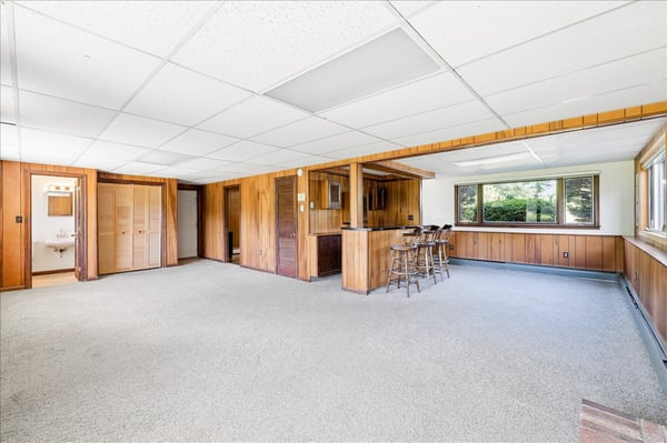 Spacious, versatile recreation area featuring a built-in bar and ample natural light from large windows.