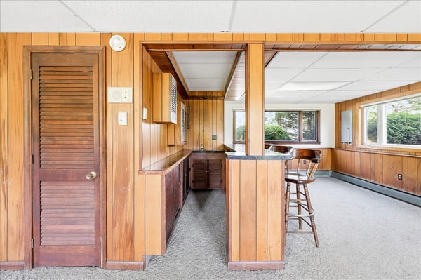 Spacious bonus room featuring natural light, wood paneling, and a convenient wet bar for entertaining.