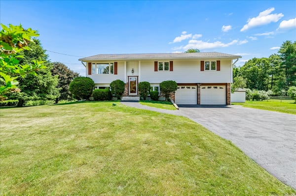 Spacious split-level home with ample yard space, featuring a welcoming entrance and dual garages.