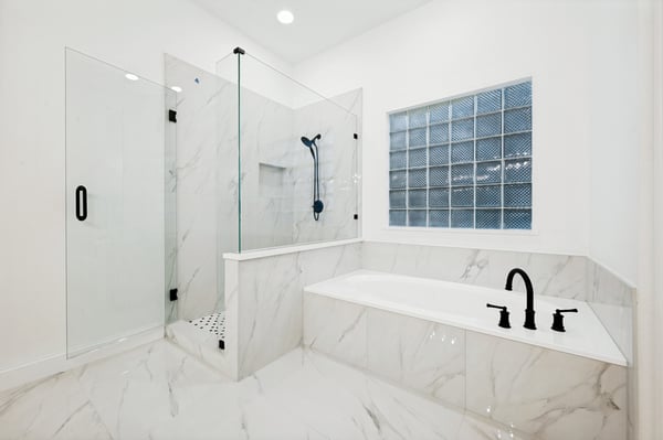 Modern bathroom featuring a glass shower, soaking tub, and sleek marble accents for a luxurious experience.